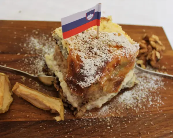 Una fetta di torta con bandierina slovena, noci e mele essiccate, un assaggio dei piatti tipici sloveni.