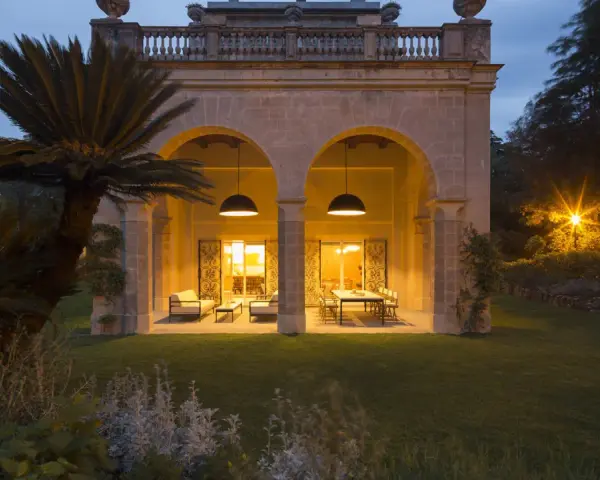 Villa Carrara a Genova, con portico illuminato e giardino serale.