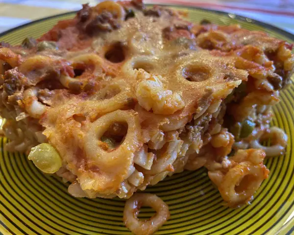 Un pezzo di pasta al forno con ragù e piselli, un'idea gustosa per cosa mangiare a Palermo.