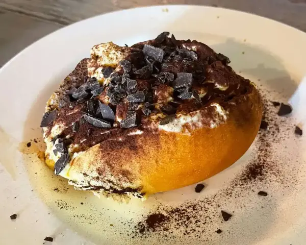 Un dolce al cucchiaio, forse un tiramisù rivisitato, con cacao e scaglie di cioccolato. Un'idea golosa su cosa mangiare a Roma.