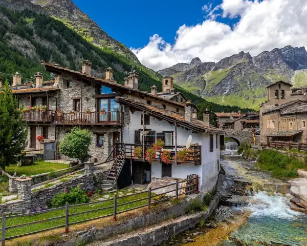 Un incantevole borgo da visitare in Piemonte, con case in pietra, balconi fioriti e un torrente che scorre tra le montagne.