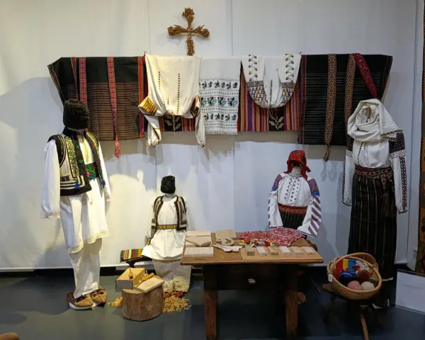 A Bucarest a dicembre, un'esposizione di abiti tradizionali rumeni, con manichini che indossano ricchi ricami e tessuti colorati.