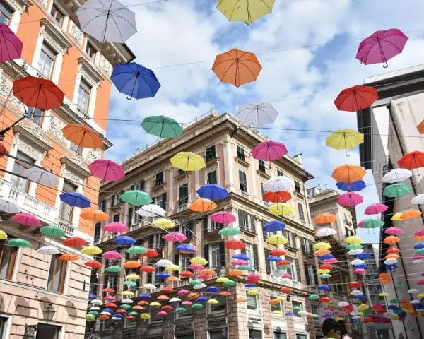 Un cielo di ombrelli colorati sopra i palazzi di Genova. Un'installazione suggestiva, perfetta per scoprire cosa vedere a Genova in 3 giorni.