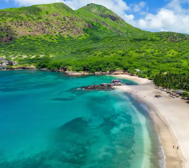 Spiaggia tropicale con mare turchese e montagne verdi. Un vero capo verde, ideale per una vacanza da sogno.
