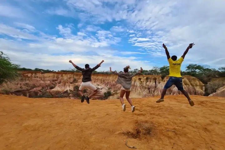 Tre amici saltano felici in Kenya, un'esperienza indimenticabile che vale ogni euro del costo safari Kenya.