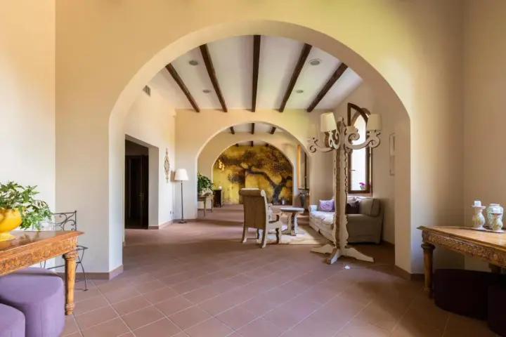 Interno accogliente con archi in pietra, un murale di un albero antico e arredi che evocano l'atmosfera dell'antico borgo di Sutri.