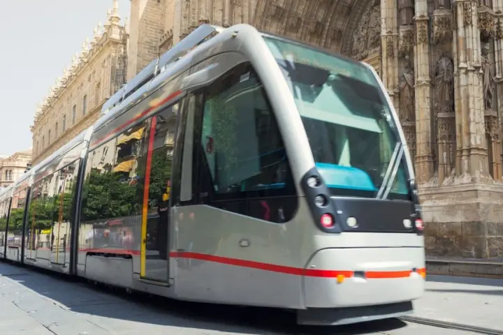 Tram moderno sfreccia davanti alla cattedrale, un modo efficiente per capire come muoversi a Siviglia.