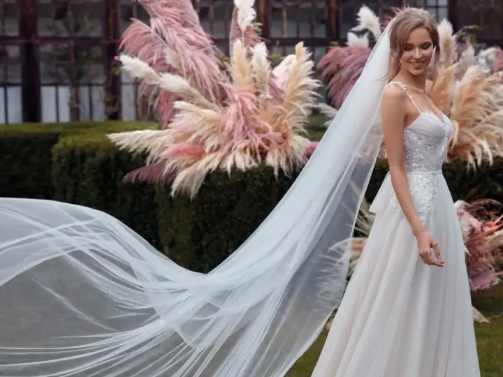 La sposa sorride, il suo abito bianco e il velo fluttuano dolcemente tra le pampas rosa.