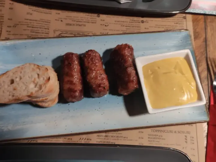 Mici e pane: un assaggio di cosa mangiare a Bucarest. Salsicce grigliate servite con pane fresco e senape.