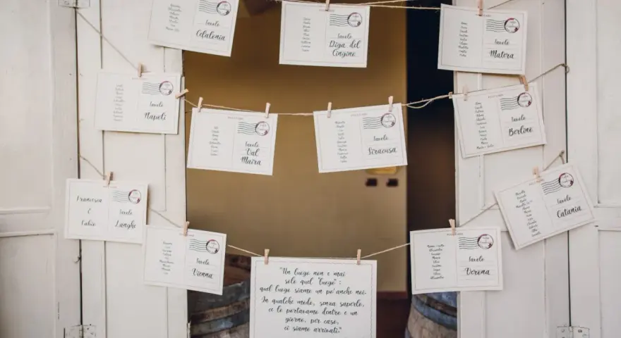 Tableau mariage idee: cartoline con nomi degli invitati e destinazioni, appese a filo con mollette.