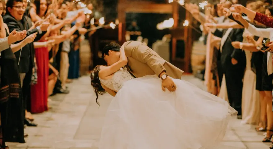 La sposa e lo sposo si baciano tra le scintille dei bengala, circondati da amici e parenti festanti. Un momento magico che sembra uscito da un gioco.