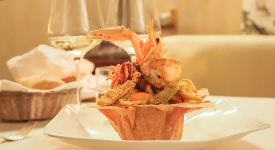 Frittura di pesce croccante, un'ottima idea per dove mangiare a Padova spendendo poco. Accompagnata da vino bianco e pane fresco.