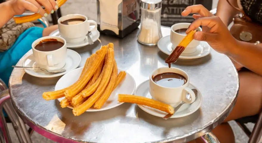 Assaporare i churros con cioccolata calda è un must per sapere cosa mangiare a Madrid. Un'esperienza golosa da condividere.