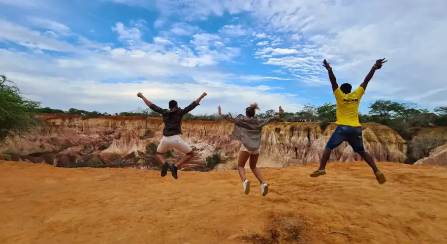Tre amici saltano felici in Kenya, un'esperienza indimenticabile che vale ogni euro del costo safari Kenya.