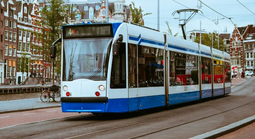 Un tram bianco e blu sferraglia sui binari, un modo efficiente per capire come muoversi ad Amsterdam tra case storiche e canali.