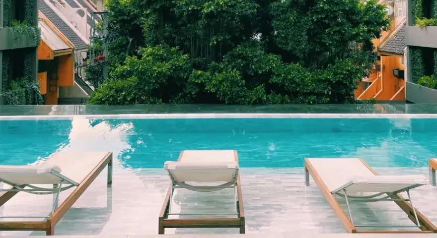 Piscina con lettini e vegetazione lussureggiante, un'oasi perfetta per sapere dove dormire a Bangkok.
