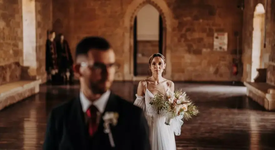 La sposa, con un bouquet rustico, attende il suo sposo in un'antica sala. Un venerdì speciale per sposarsi.
