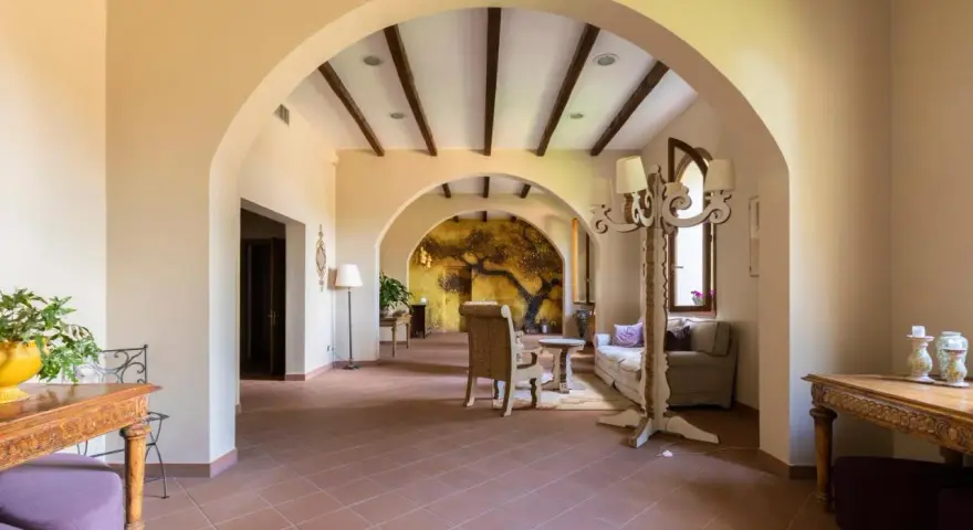 Interno accogliente con archi in pietra, un murale di un albero antico e arredi che evocano l'atmosfera dell'antico borgo di Sutri.