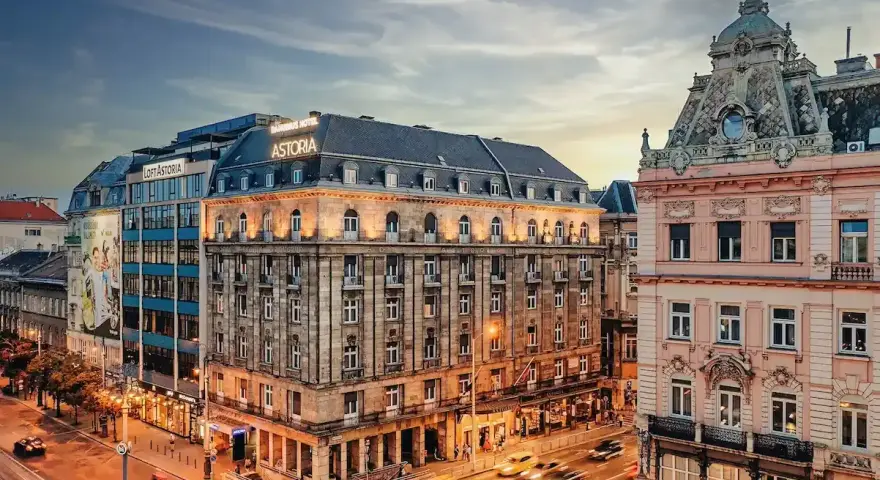 Hotel Astoria, un'ottima scelta per dove alloggiare a Budapest, si affaccia su una strada trafficata con auto gialle sfocate.