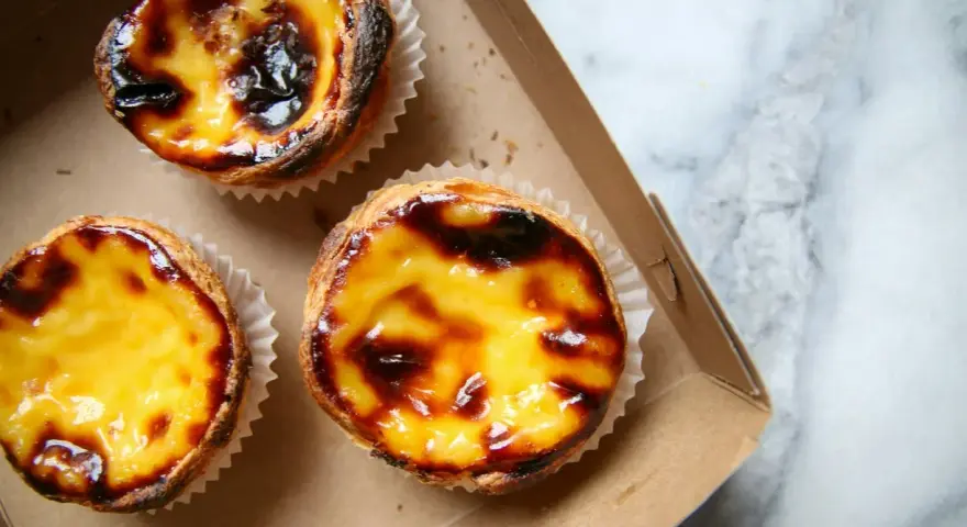 Pastéis de nata appena sfornati, un must per scoprire cosa mangiare a Lisbona. Croccanti fuori, cremosi dentro.