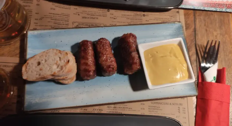 Mici e pane: un assaggio di cosa mangiare a Bucarest. Salsicce grigliate servite con pane fresco e senape.