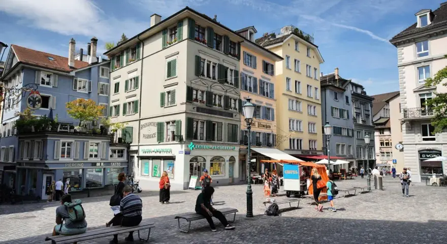 Piazza di Zurigo con edifici colorati, negozi e persone che passeggiano. Ideale per scoprire cosa vedere a Zurigo in un giorno.