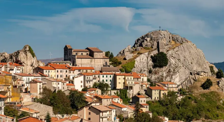 Borgo arroccato con case dai tetti rossi, una chiesa imponente e una roccia con croce in cima. Un luogo da scoprire tra le meraviglie di cosa vedere in Molise.