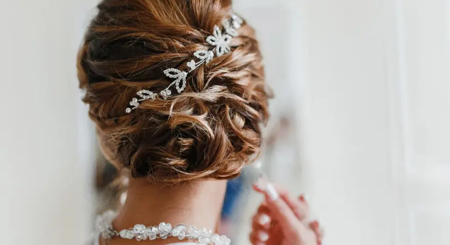 Splendida acconciatura alta sposa con fermaglio scintillante e collana di perle.