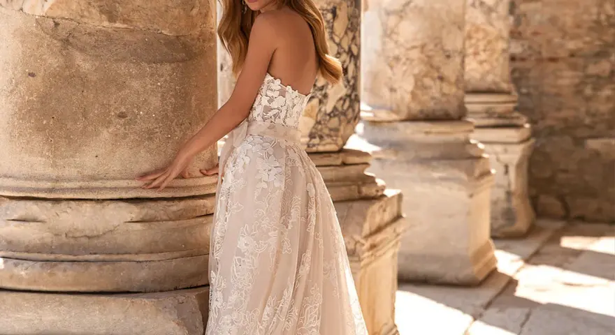 Modella con un abito da sposa in pizzo, tra colonne antiche. Il costo abito da sposa è un investimento per un sogno.