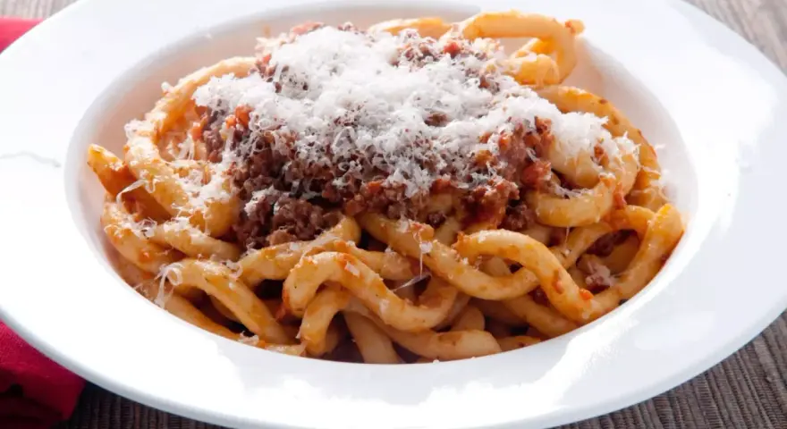 Pici al ragù, un classico da provare per scoprire cosa mangiare a Siena. Pasta fatta a mano con sugo di carne e abbondante pecorino.