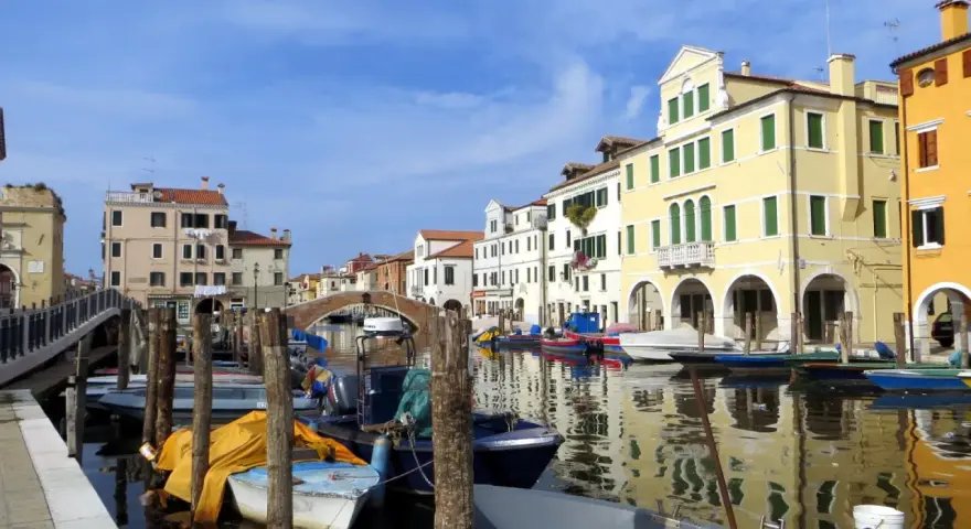 Chioggia cosa vedere: un canale con barche ormeggiate e case colorate che si riflettono sull'acqua.