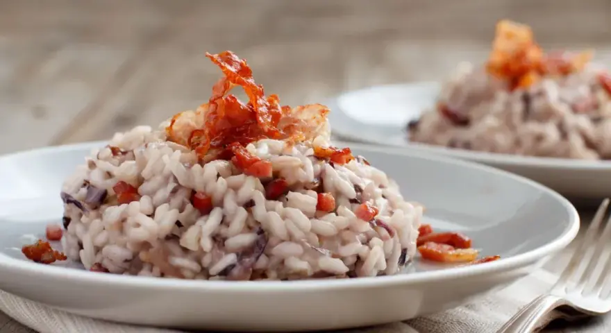 Risotto cremoso con radicchio e pancetta croccante, un classico da provare se ti chiedi cosa mangiare a Treviso.