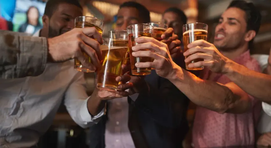 Amici brindano con birra in un locale, un brindisi per l'addio al celibato.