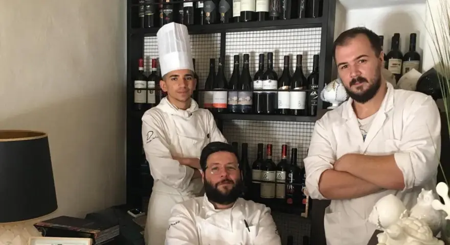 Tre chef posano davanti a una cantina di vini in un ristorante stellato Puglia.