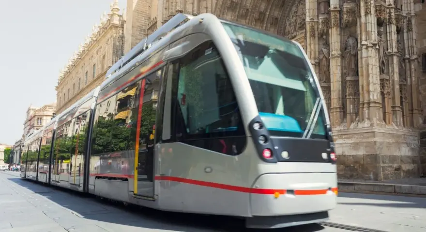 Tram moderno sfreccia davanti alla cattedrale, un modo efficiente per capire come muoversi a Siviglia.