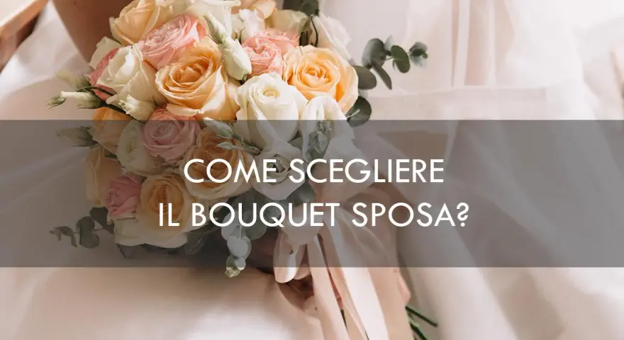 Un bouquet sposa elegantissimo con rose pesca, rosa e bianche, tenuto da una sposa.
