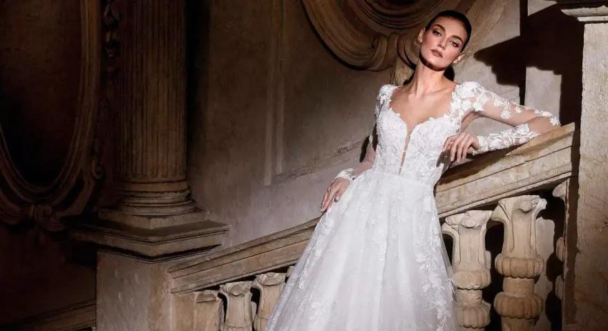 Modella con abiti da sposa per sembrare più alte, posa su una scala di pietra antica.