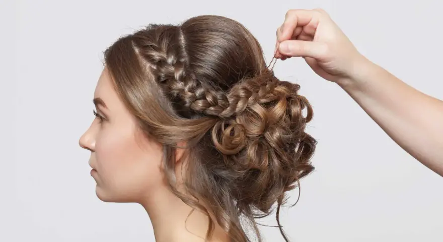 Treccia semiraccolto, un'acconciatura sposa elegante con ricci morbidi e una mano che aggiunge un fermaglio.
