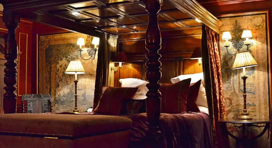 Lussuosa camera da letto con letto a baldacchino, arazzi storici e lampade eleganti. Un'idea di dove dormire a Edimburgo per un soggiorno da re.