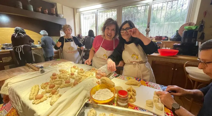 Donne sorridenti preparano impasti per piatti tipici di Perugia, con uova e pane intrecciato.