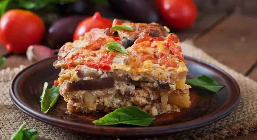 Un assaggio di cosa mangiare a Santorini: una saporita moussaka con melanzane, pomodori e formaggio, guarnita con basilico fresco.