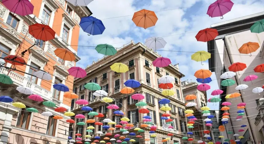 Un cielo di ombrelli colorati sopra i palazzi di Genova. Un'installazione suggestiva, perfetta per scoprire cosa vedere a Genova in 3 giorni.