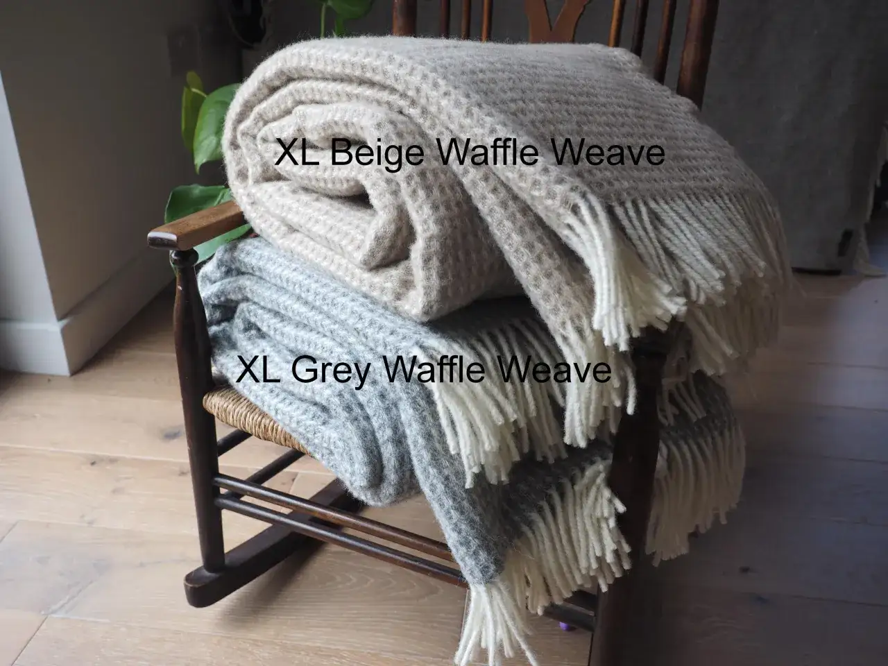 Coperte XL a trama waffle, beige e grigia, su una sedia a dondolo. Perfette per celebrare le nozze 7 anni con calore e stile.