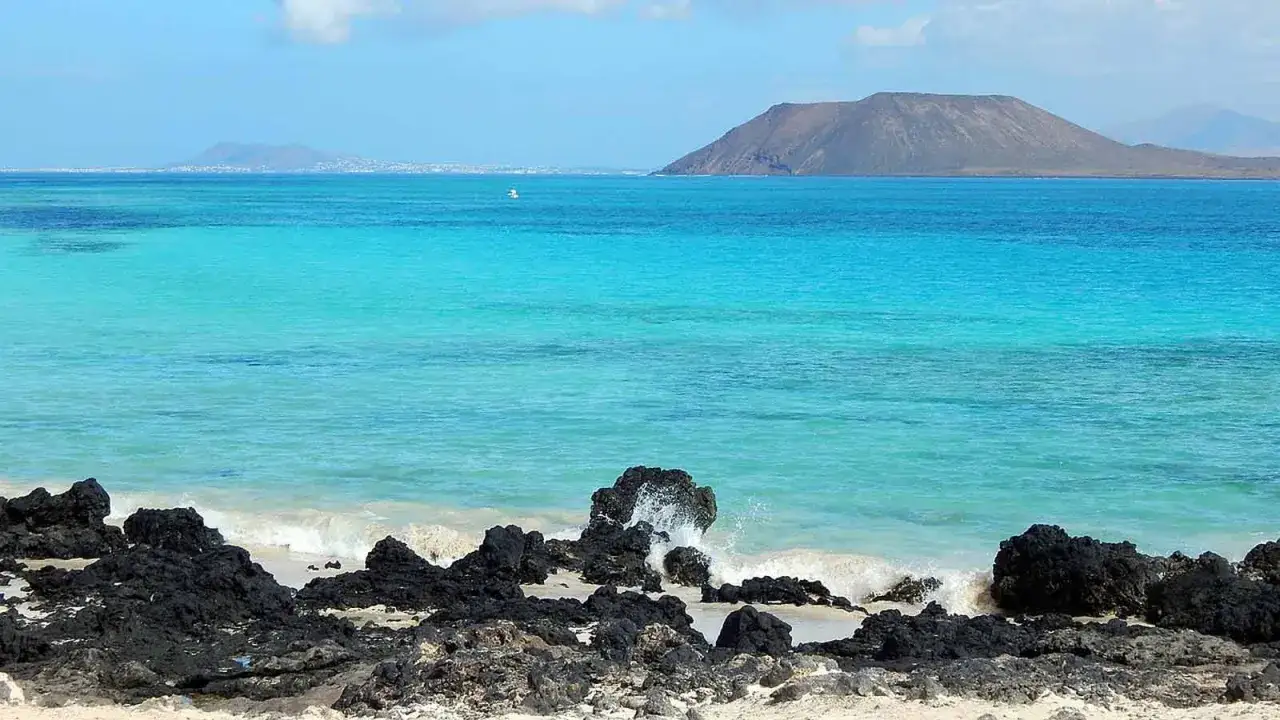 Spiaggia con rocce laviche e mare turchese. Un luogo ideale per pensare a dove andare al mare a Capodanno.