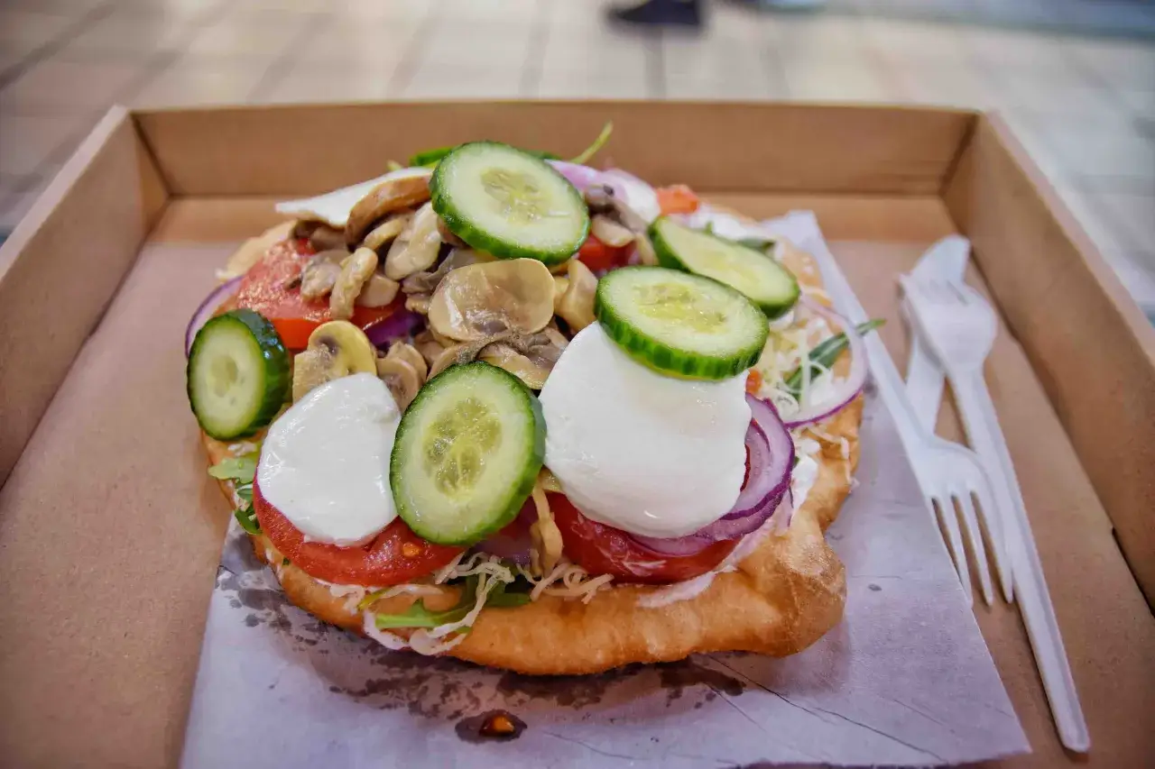 Lángos con pomodoro, mozzarella, cetrioli, cipolla rossa e funghi. Un'ottima idea per cosa mangiare a Budapest.