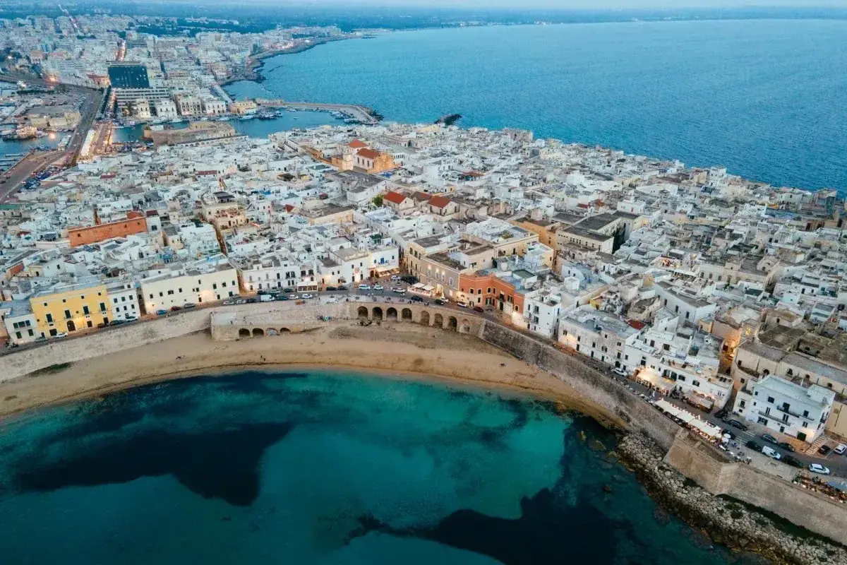 Vista aerea di Gallipoli, con case bianche, mare turchese e un arco storico. Perfetto per scoprire cosa fare a Gallipoli.