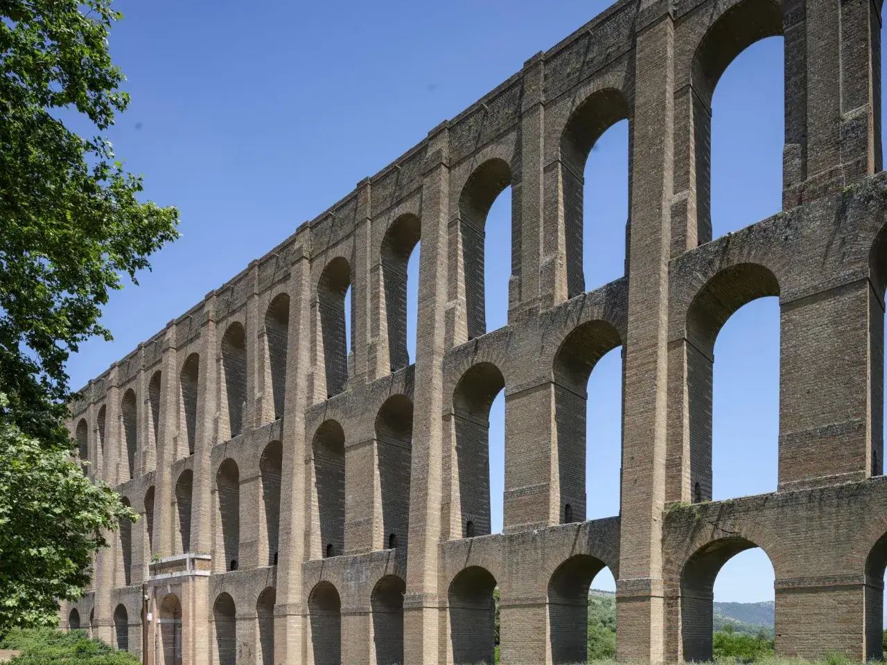 Imponente acquedotto romano con archi sovrapposti, un'opera che ricorda i mulini reali per la sua grandezza e ingegneria.