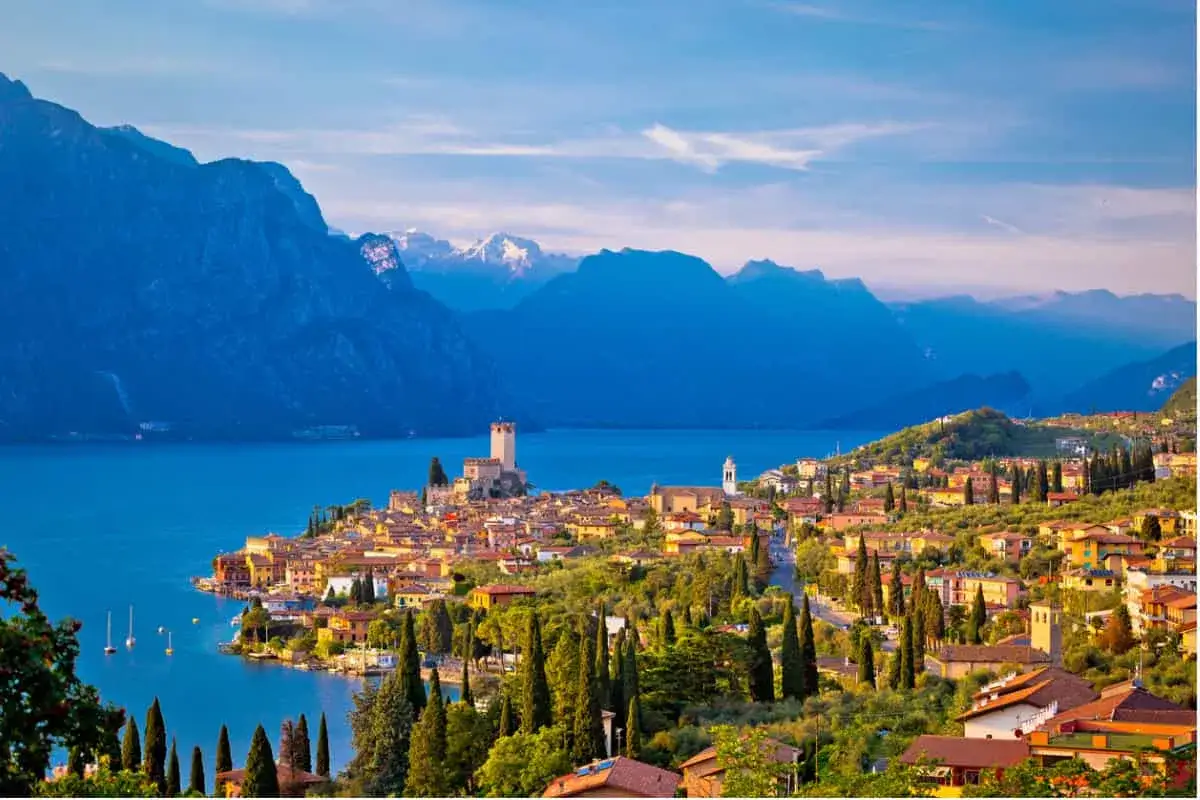 Borgo sul lago con castello e montagne sullo sfondo. Perfetto per le tue idee weekend Italia.