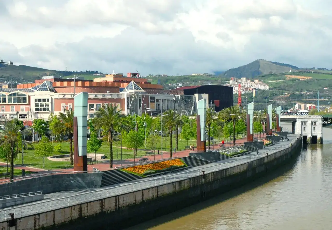 Passeggiata lungo il fiume Nervión, ideale per scoprire cosa vedere a Bilbao in 3 giorni: palme, aiuole fiorite e architetture moderne.