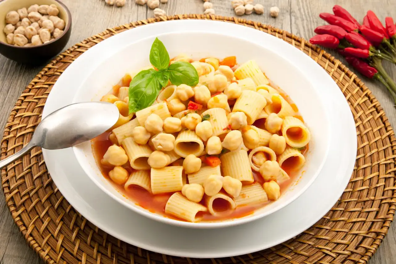 Un piatto di pasta e ceci, un classico su cosa mangiare a Pisa. Servito con basilico fresco e peperoncini rossi.
